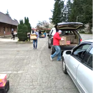 Volunteers loading donated food into a car trunk at a Salt of the Earth drive-thru distribution event in Snohomish County