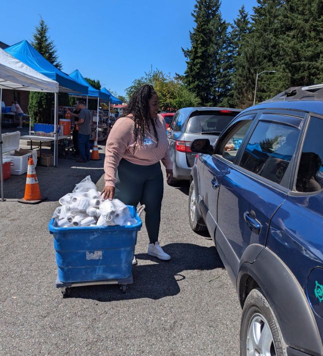 Volunteer serving people in vehicles at a food distribution