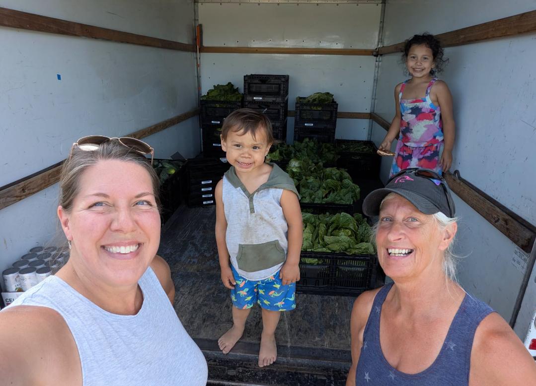 Children smiling inside a truck filled with fresh produce