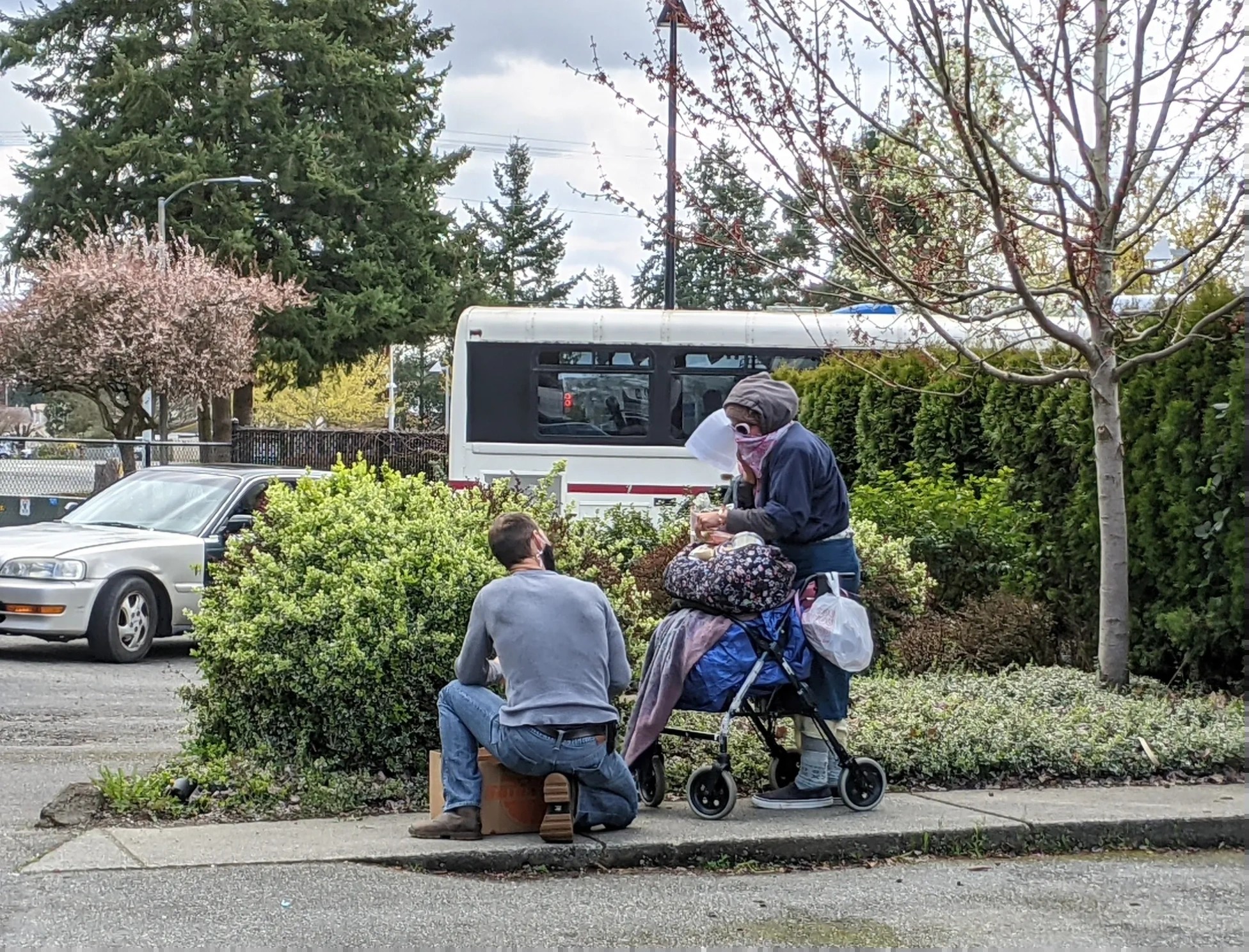 A Salt of the Earth volunteer kneeling to assist an elderly woman with a walker, delivering food to those in need in Snohomish County